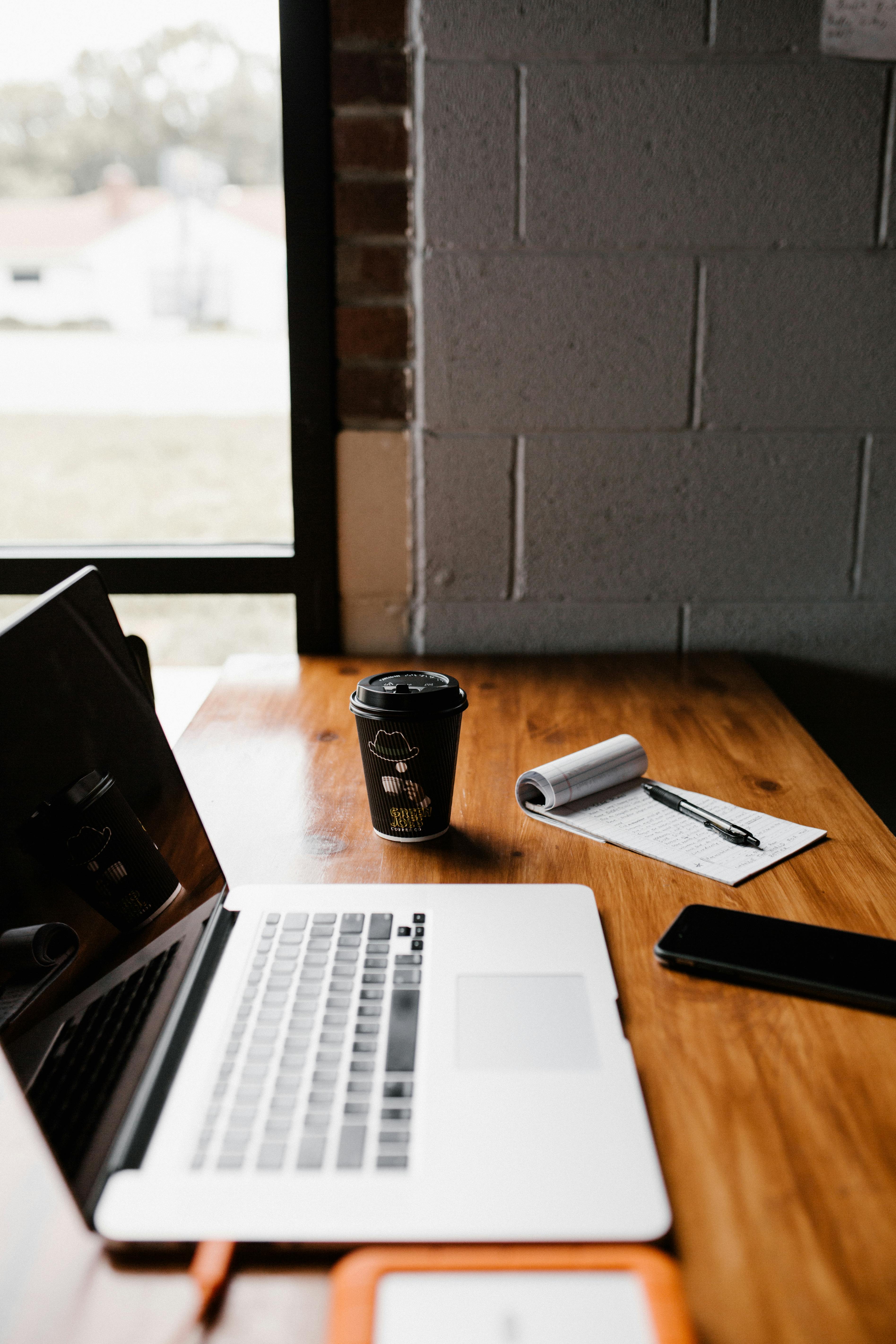 Laptop on a table near a bright window and plant