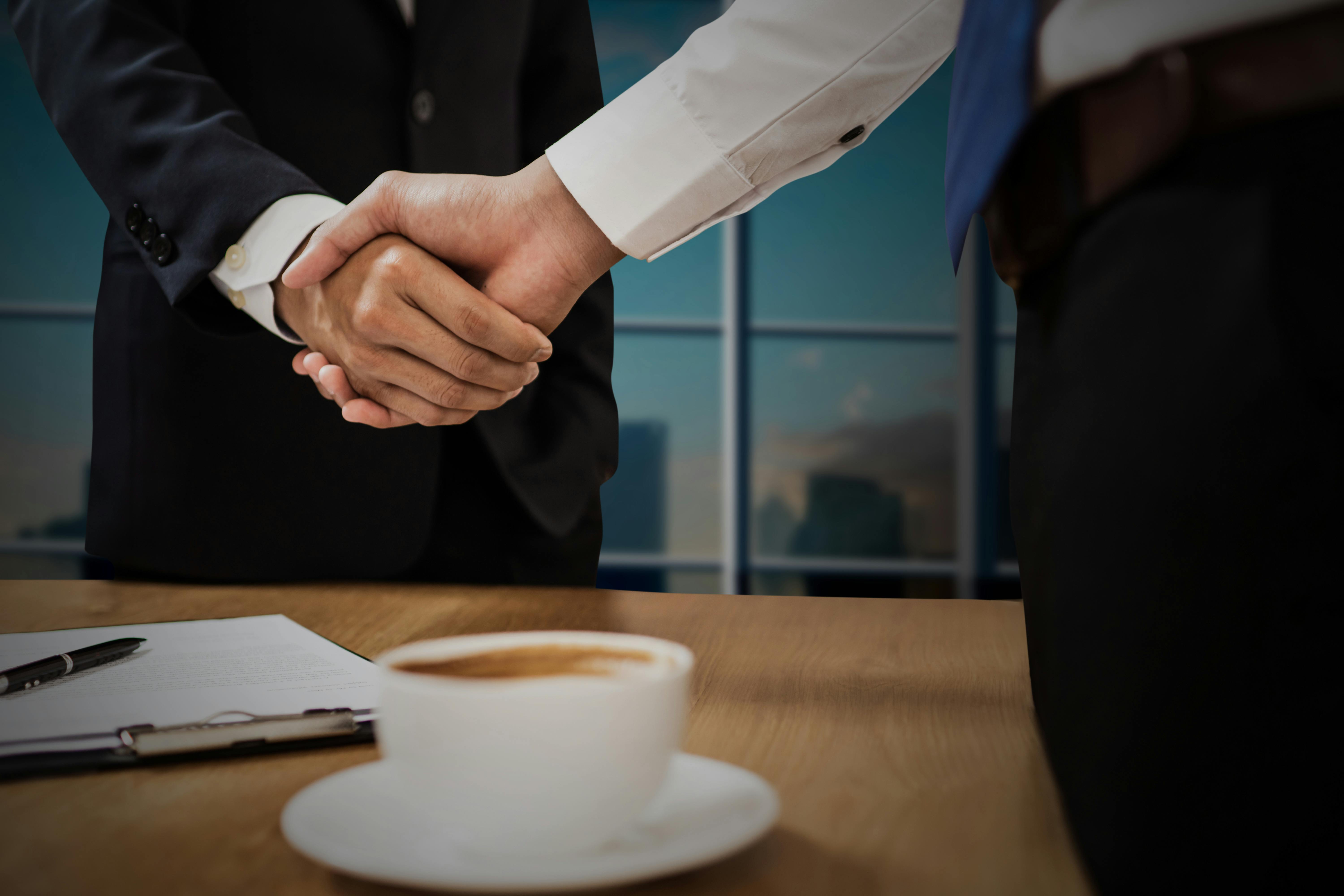 Handshake across a desk with city view behind