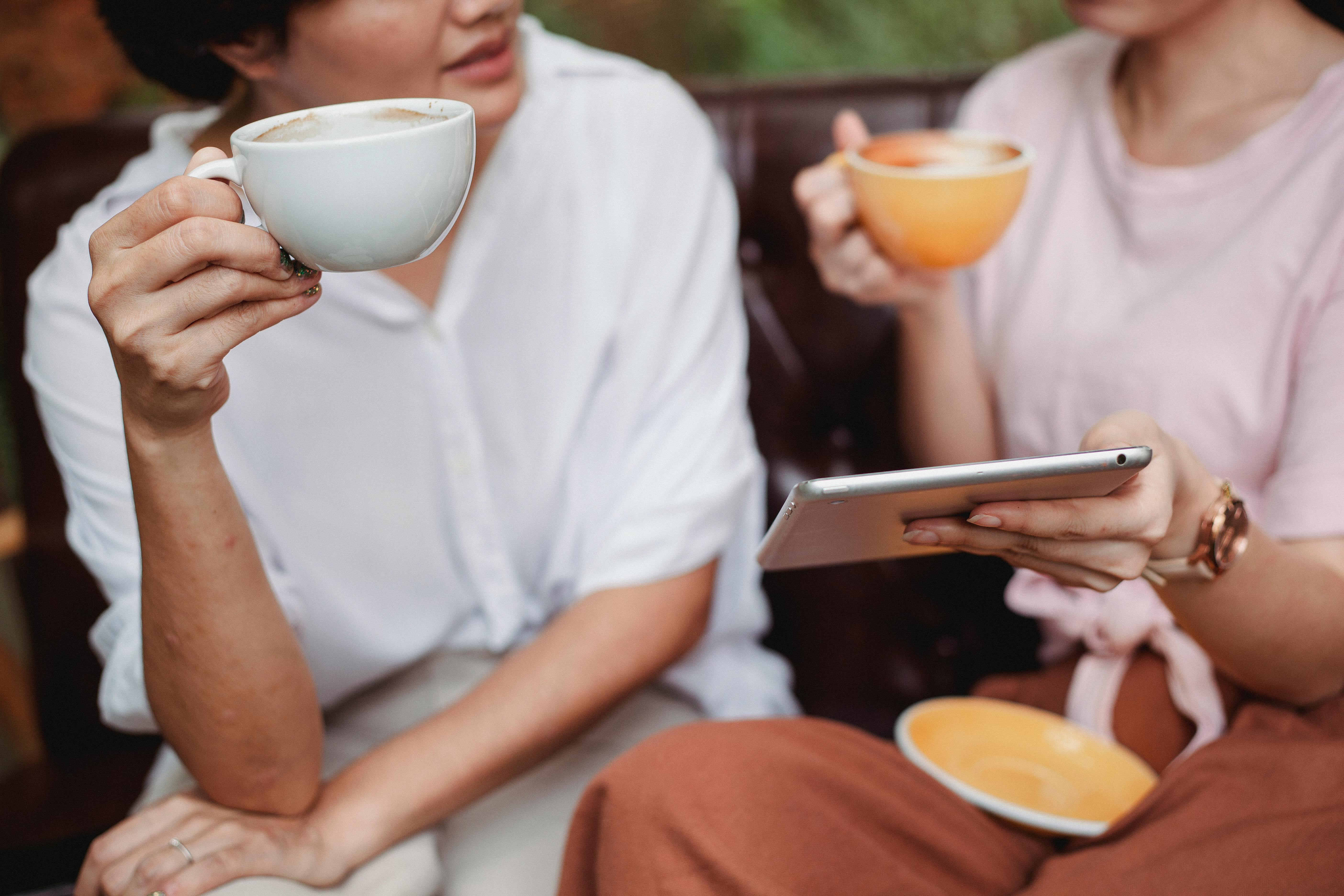 People using a tablet and drinking coffee during a discussion